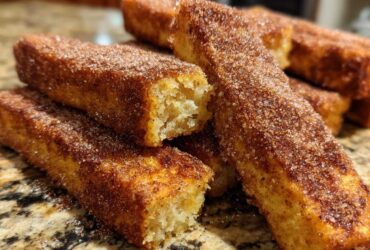 Close-up of golden brown Air Fryer French Toast Sticks heavily coated in cinnamon sugar.