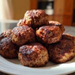 A mound of golden-brown, perfectly cooked Air Fryer Italian Meatballs stacked high on a white plate.