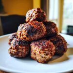 A stack of perfectly cooked, browned Air Fryer Italian Meatballs resting on a white plate.