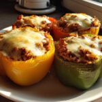 Four colorful Air Fryer Stuffed Bell Peppers, topped with melted mozzarella cheese, served on a white plate.
