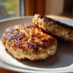 Close-up of two juicy Air Fryer Turkey Burgers with a beautiful golden-brown sear on a white plate.