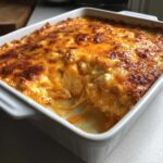 A close-up of hot, bubbly Baked Buffalo Chicken Dip with a golden-brown, melted cheese topping in a white baking dish.