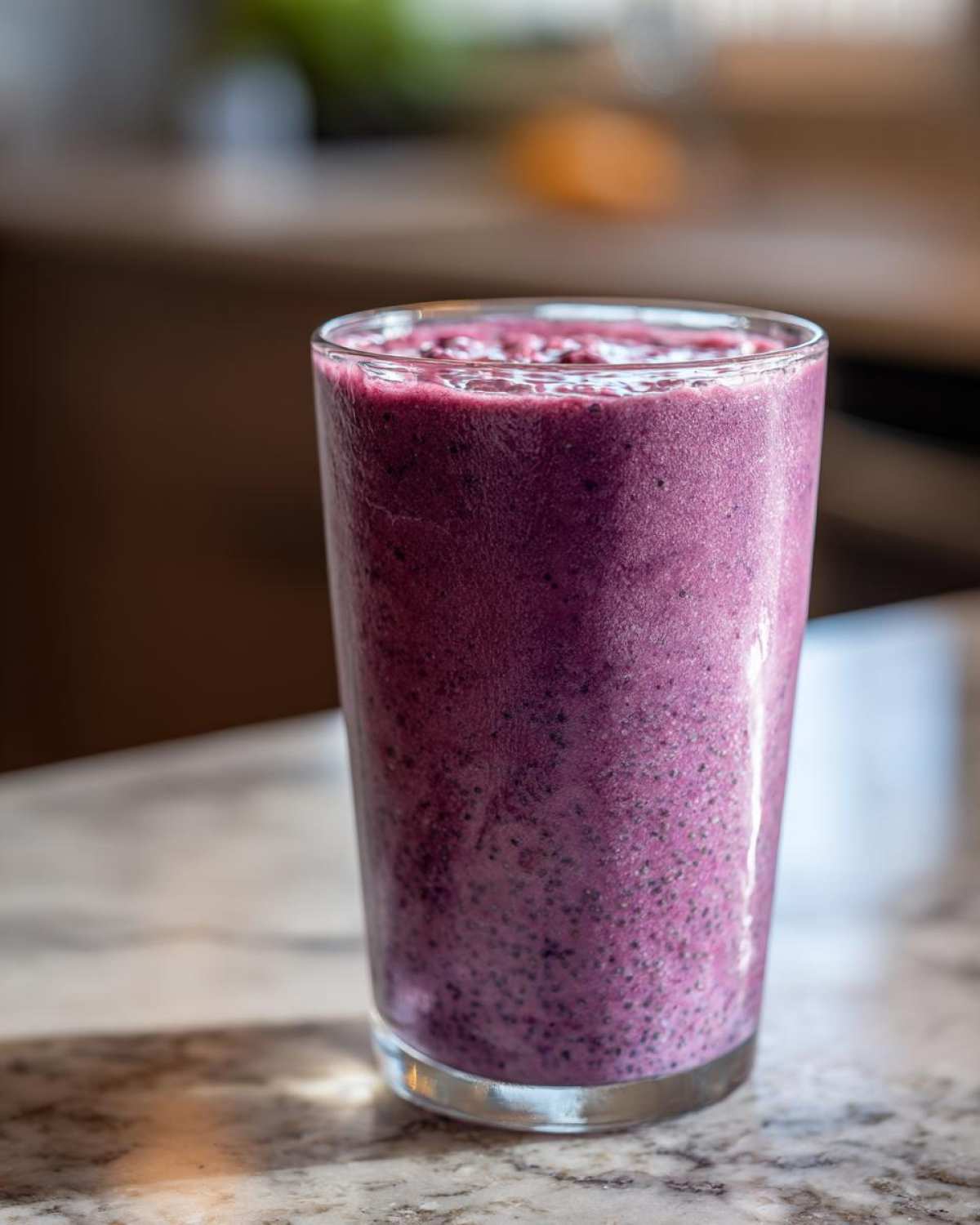 Close-up of a tall glass filled with a thick, vibrant purple Blueberry Lemon Chia Smoothie.