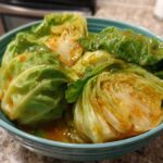 Close-up of wedges of Cabbage Stir Fry with Garlic Ginger Sauce coated in a glossy orange sauce in a teal bowl.