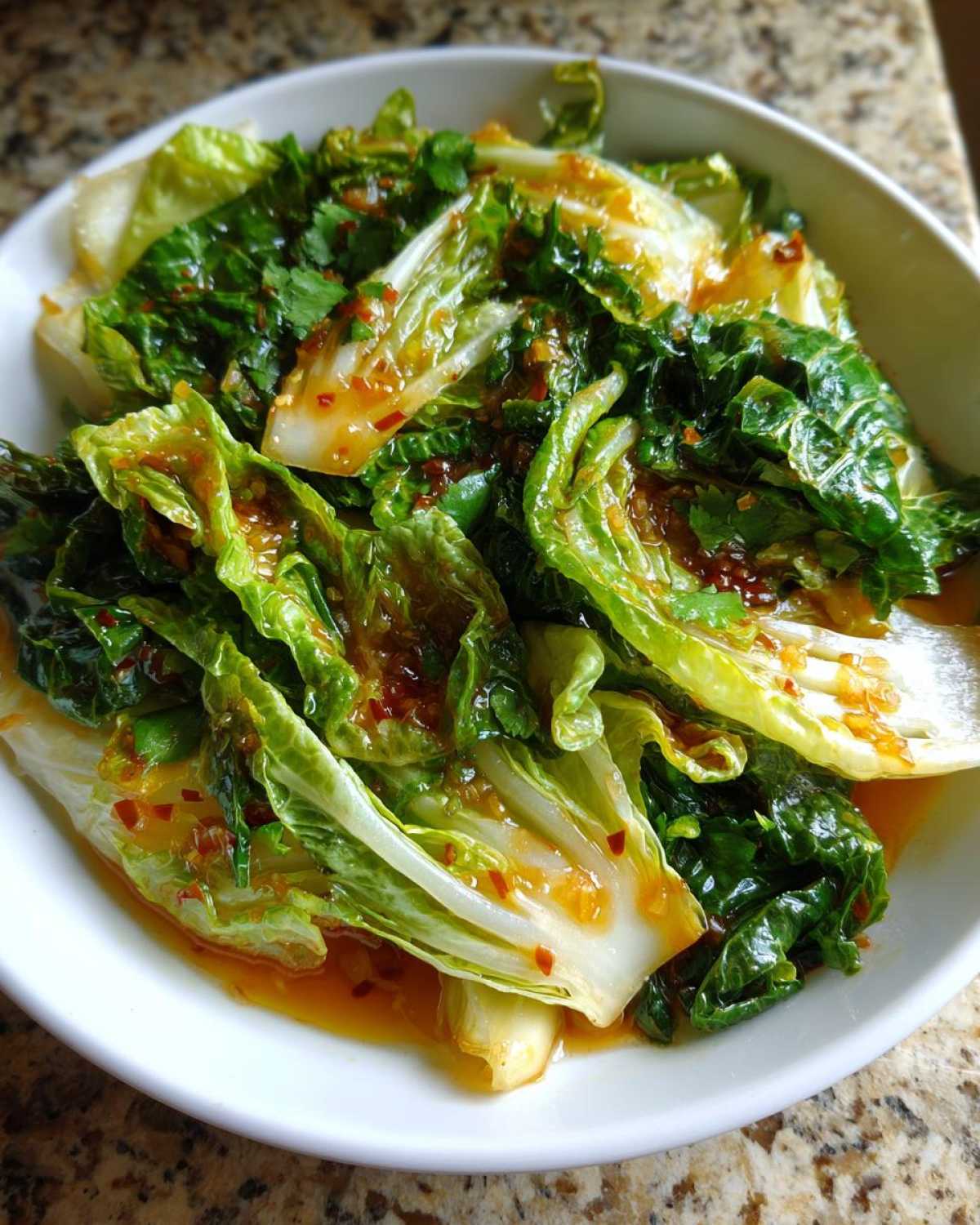 Close-up of vibrant Cabbage Stir Fry with Garlic Ginger Sauce, glistening in a white bowl.