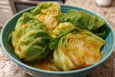 Close-up of wedges of Cabbage Stir Fry with Garlic Ginger Sauce coated in a glossy orange sauce in a teal bowl.