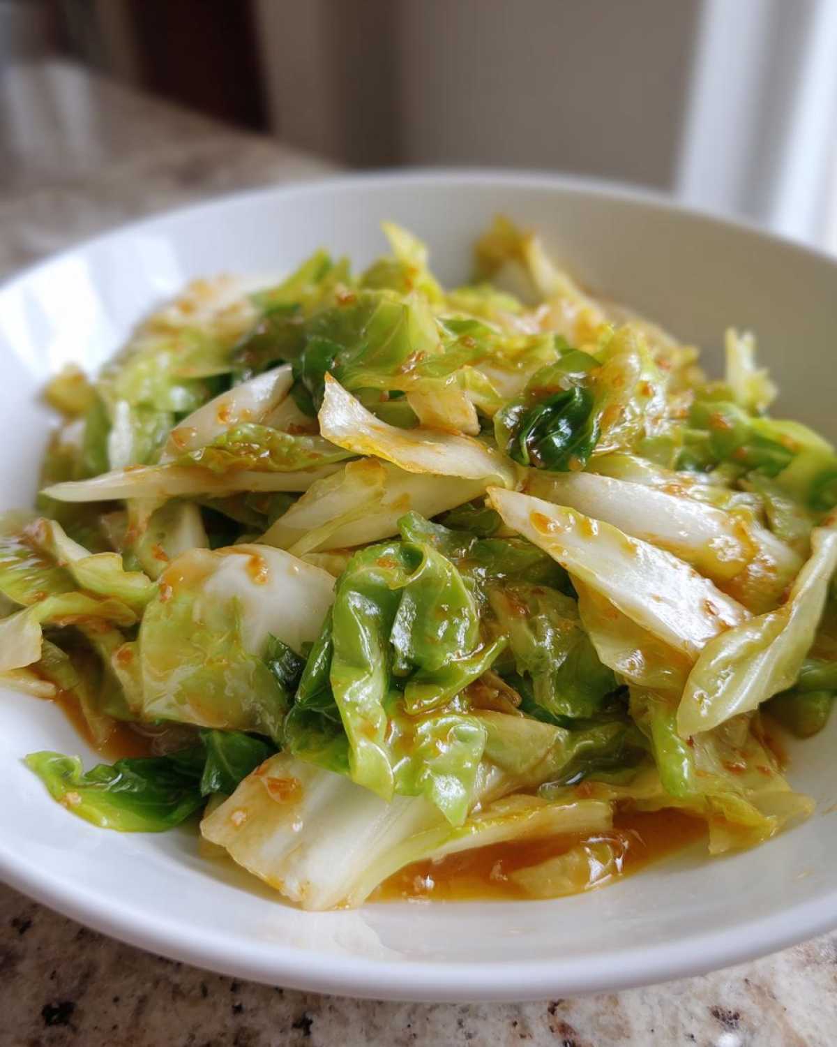 A close-up of vibrant Cabbage Stir Fry with Garlic Ginger Sauce served in a white bowl.