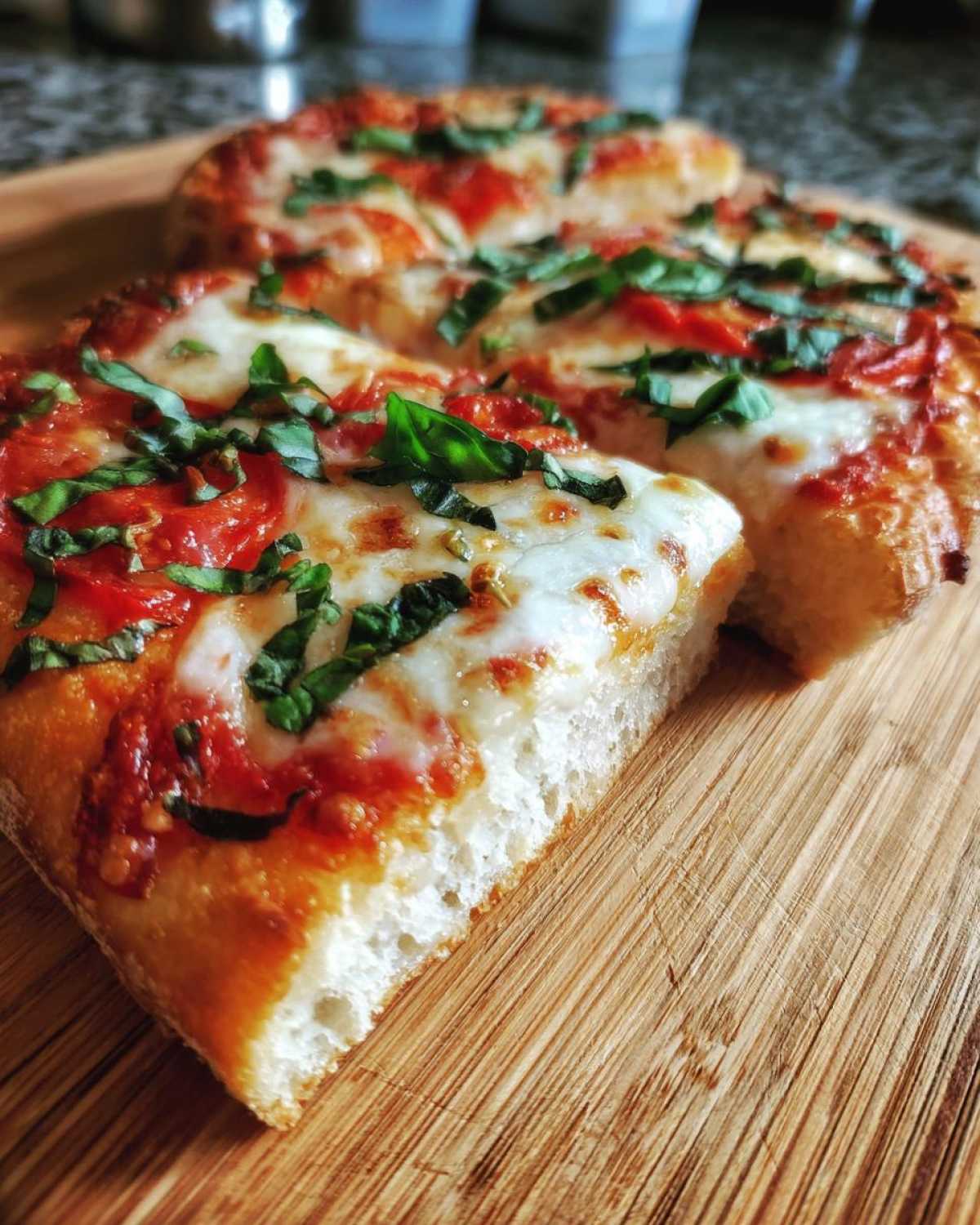 Close-up of a thick, chewy slice of Gluten-Free Margherita Pizza topped with melted mozzarella, tomato sauce, and fresh basil.
