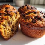 Close-up of moist Chocolate Chip Banana Muffins, one split open showing the texture.