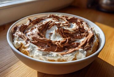A white bowl filled with creamy Chocolate Peanut Butter Cheesecake Dip, swirled with chocolate topping.