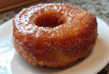A close-up of a perfectly cooked, golden Cinnamon Sugar Air Fryer Donut coated in glistening sugar.