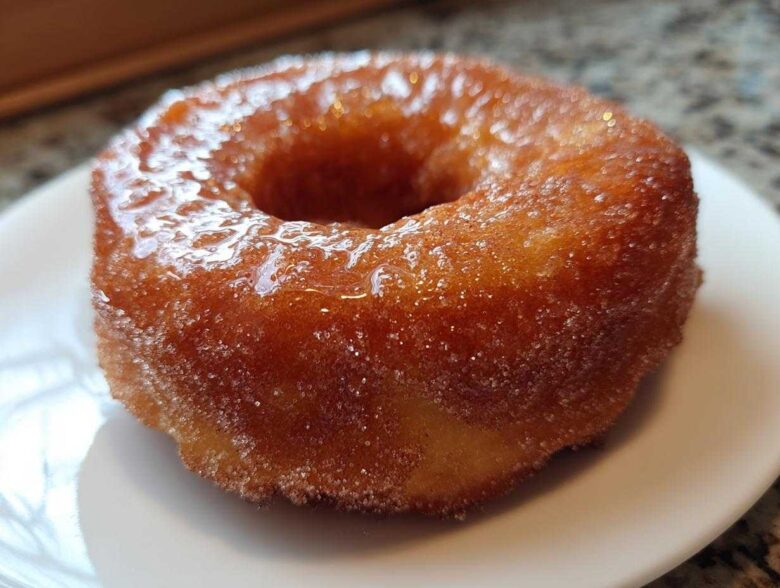 A close-up of a perfectly cooked, golden Cinnamon Sugar Air Fryer Donut coated in glistening sugar.