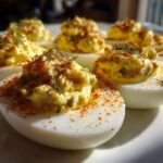 Close-up of several Classic Deviled Eggs with Dill Pickle Relish, topped with paprika and fresh dill.