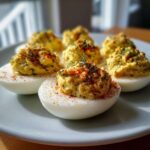 Close-up of several Classic Deviled Eggs with Dill Pickle Relish, topped with paprika and fresh dill.