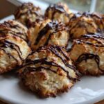 A plate filled with golden-brown Coconut Macaroons with Dark Chocolate Drizzle, featuring toasted edges.