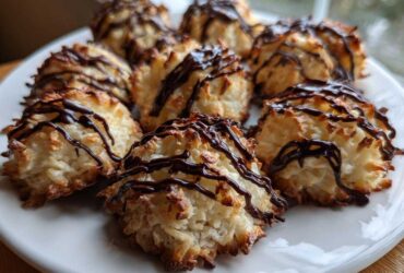 A plate filled with golden-brown Coconut Macaroons with Dark Chocolate Drizzle, featuring toasted edges.