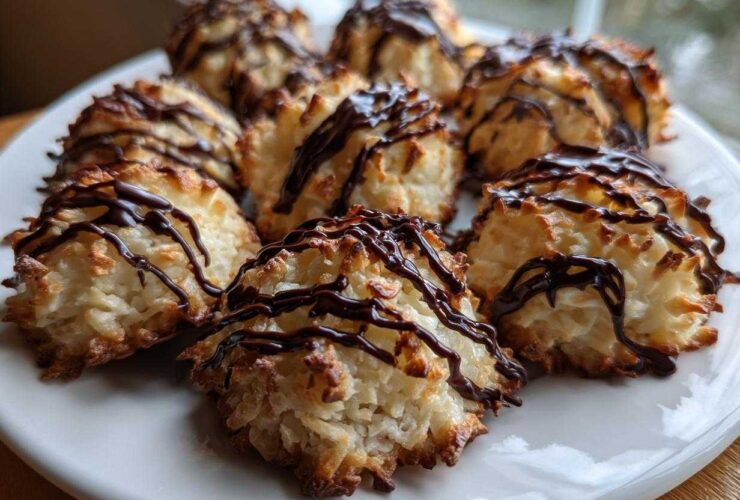 A plate filled with golden-brown Coconut Macaroons with Dark Chocolate Drizzle, featuring toasted edges.