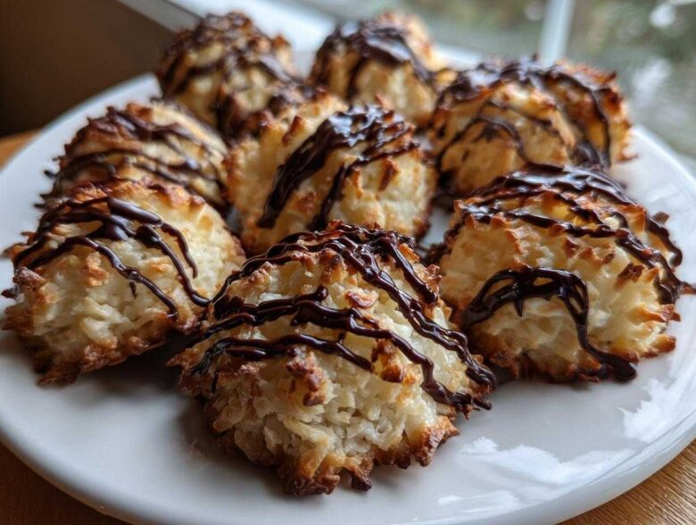 A plate filled with golden-brown Coconut Macaroons with Dark Chocolate Drizzle, featuring toasted edges.