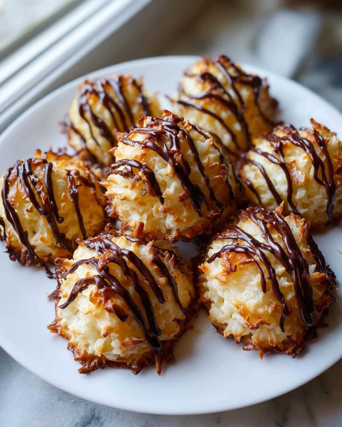 A plate of freshly baked Coconut Macaroons with Dark Chocolate Drizzle, featuring toasted edges.