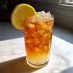A tall glass filled with layered Cold Brew Lemonade, crushed ice, and a lemon wheel garnish.