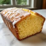 A moist, yellow loaf cake, resembling the Copycat Starbucks Iced Lemon Loaf, topped with thick white lemon glaze.