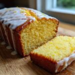 A moist Copycat Starbucks Iced Lemon Loaf cake with thick white glaze and lemon zest, next to a perfect slice.
