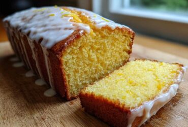 A moist Copycat Starbucks Iced Lemon Loaf cake with thick white glaze and lemon zest, next to a perfect slice.