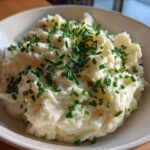 A bowl of fluffy Creamy Garlic Mashed Cauliflower topped generously with fresh, chopped green chives.