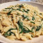 A close-up view of a bowl filled with rich Creamy Garlic Parmesan Orzo with Spinach.