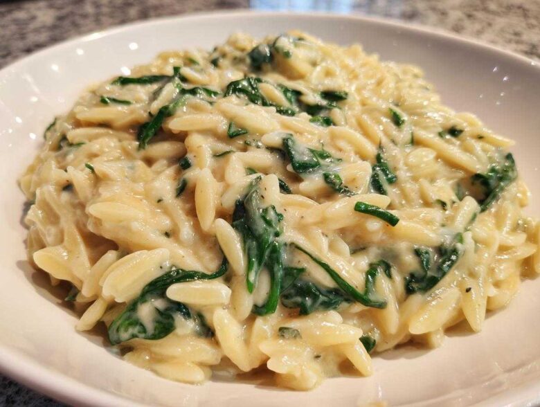 A close-up view of a bowl filled with rich Creamy Garlic Parmesan Orzo with Spinach.