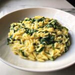 A close-up of rich, creamy Garlic Parmesan Orzo with Spinach served in a white bowl.