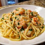 Close-up of a white bowl filled with Creamy Lemon Garlic Shrimp Pasta, topped with parsley and parmesan.