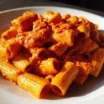 Close-up of rigatoni pasta coated in a rich, orange-red sauce, showcasing the Creamy Roasted Red Pepper Pasta.