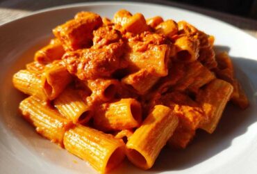 Close-up of rigatoni pasta coated in a rich, orange-red sauce, showcasing the Creamy Roasted Red Pepper Pasta.