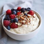 Close-up of a thick Creamy Vanilla Protein Smoothie Bowl topped with fresh mixed berries and sliced almonds.