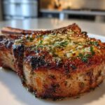 Close-up of a thick, juicy Crispy Air Fryer Pork Chop topped with melted garlic butter and fresh parsley.