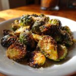 A close-up of roasted and caramelized Crispy Parmesan Brussels Sprouts sprinkled with grated cheese.