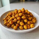 A white bowl filled with golden, seasoned Crunchy Air Fryer Ranch Chickpeas piled high.