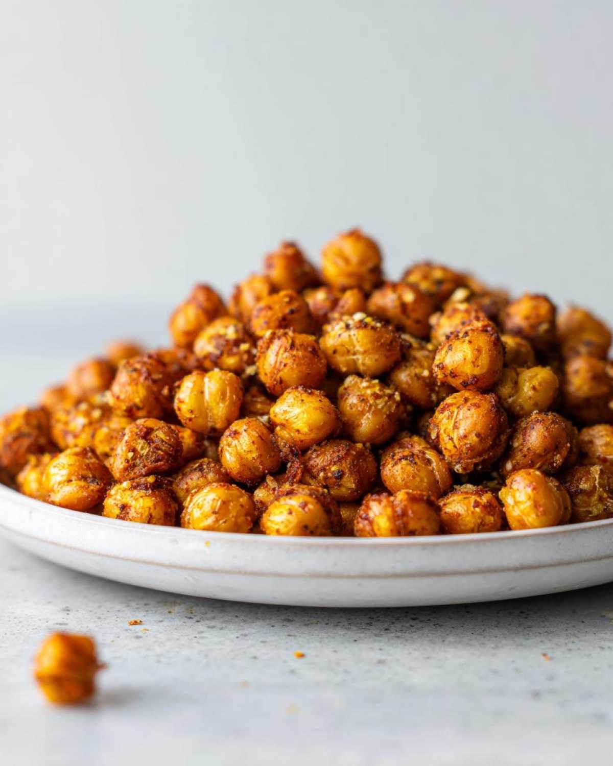 A close-up shot of a mound of golden, seasoned Crunchy Air Fryer Ranch Chickpeas piled high on a white plate.