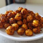 A close-up of a white plate piled high with golden brown, seasoned Crunchy Air Fryer Ranch Chickpeas.