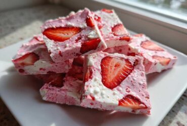 Close-up of stacked pieces of Frozen Strawberry Yogurt Bark featuring visible slices of fresh strawberries.