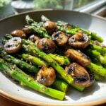 Bright green spears of Garlic Butter Roasted Asparagus and sliced, browned mushrooms served in a light bowl.
