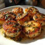 A plate of perfectly seared Garlic Butter Scallops with Lemon, glistening in butter sauce and topped with parsley.