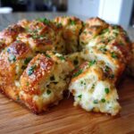 Close-up of golden brown Garlic Parmesan Pull-Apart Bread, garnished with fresh parsley, with one piece pulled away.