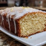 Close-up of a slice of Gluten-Free Lemon Coconut Cake drizzled with white icing and topped with coconut flakes.