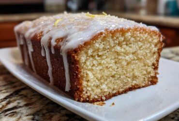 Close-up of a slice of Gluten-Free Lemon Coconut Cake drizzled with white icing and topped with coconut flakes.