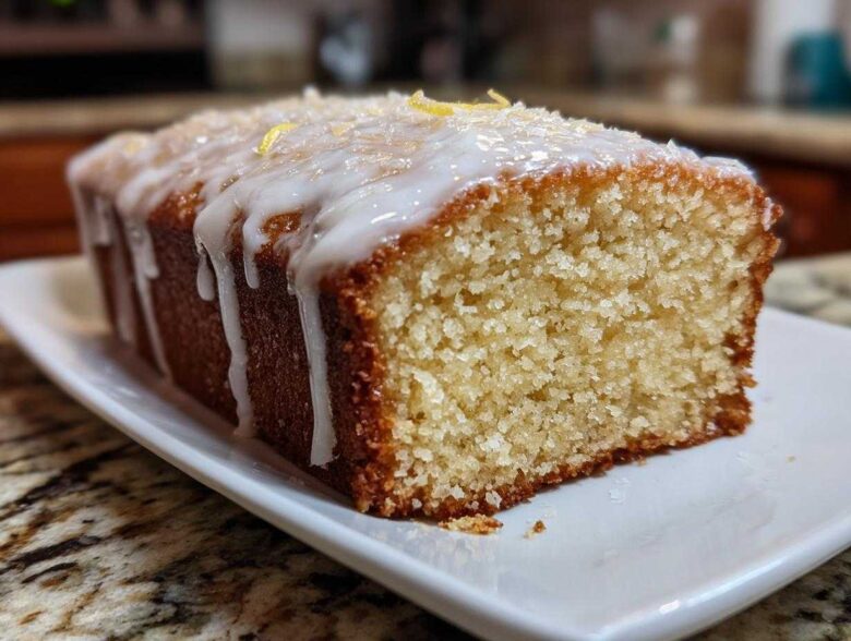 Close-up of a slice of Gluten-Free Lemon Coconut Cake drizzled with white icing and topped with coconut flakes.