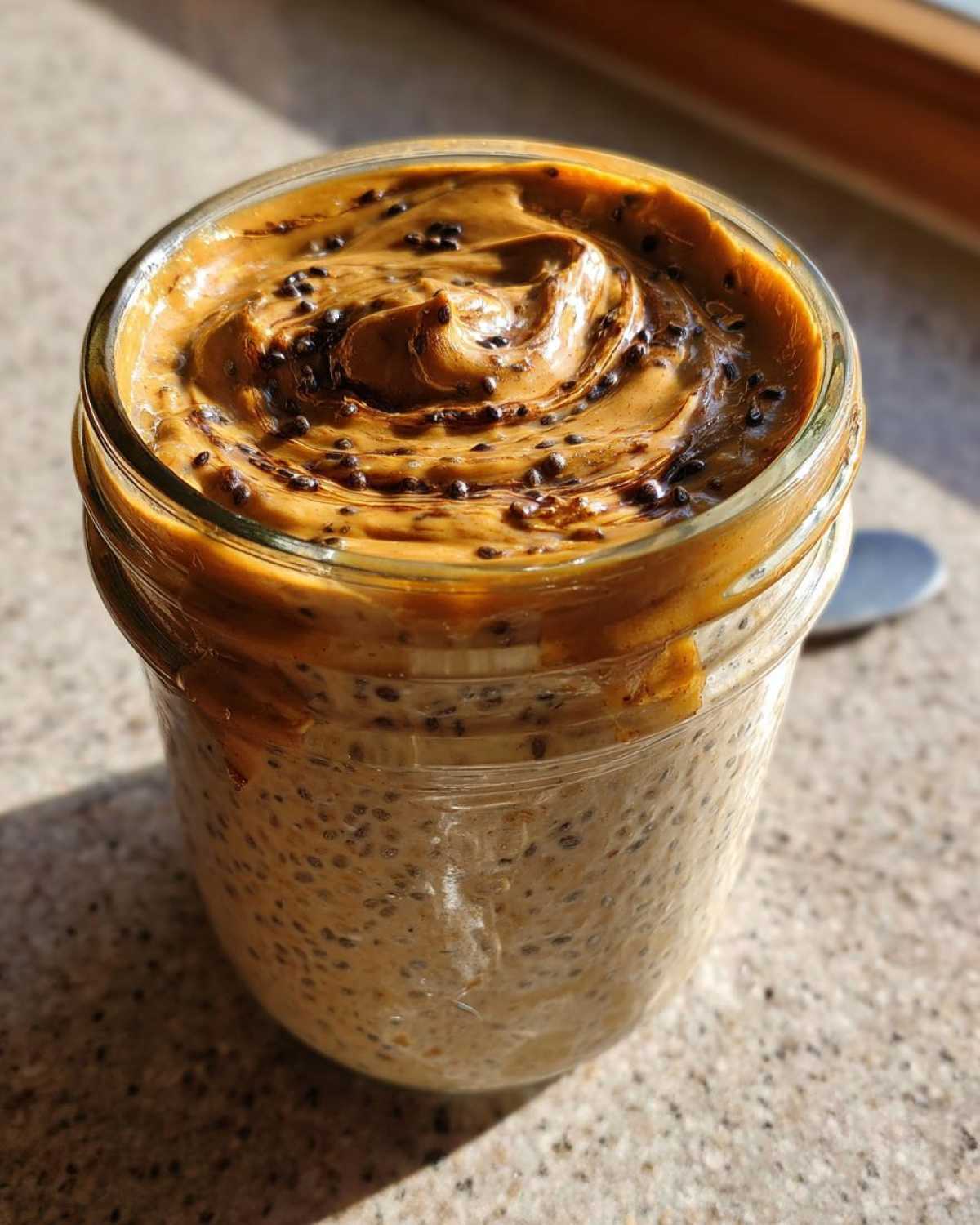 Close-up of High-Protein Peanut Butter Overnight Oats topped with swirled peanut butter and chia seeds.