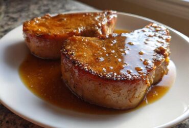 Two thick slices of Honey Glazed Ham Steak in the Skillet, glistening with sweet brown glaze on a white plate.