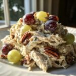 A mound of creamy Honey Mustard Chicken Salad with Grapes and pecans served on a white plate.
